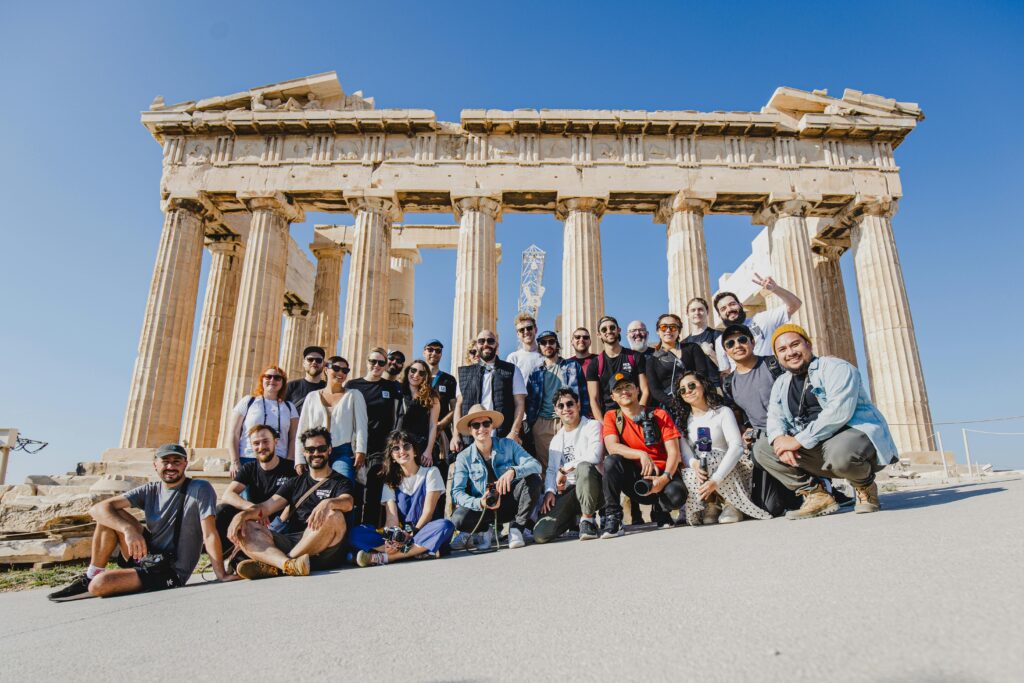 pexels-photo-14385272-14385272 A group photo of tourists in front of the Parthenon, Athens, Greece under a clear blue sky.
